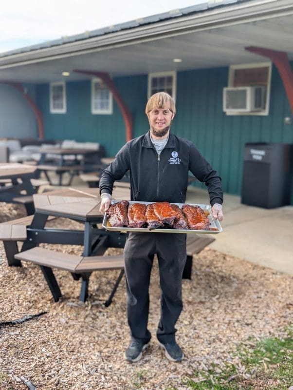A man holding a fresh tray of smoked meat.