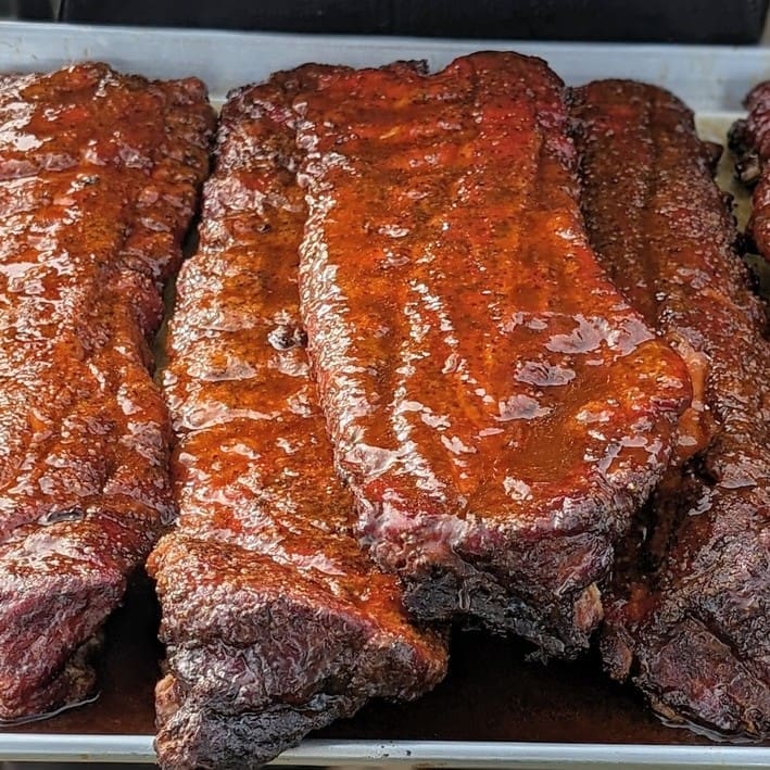 A tray of several racks of ribs as seen from above.